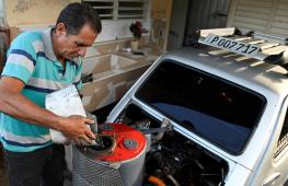 Кубинец в условиях дефицита бензина заправляет автомобиль углём