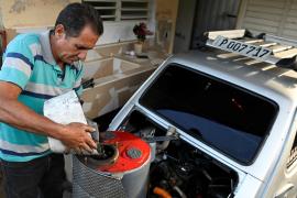 Кубинец в условиях дефицита бензина заправляет автомобиль углём